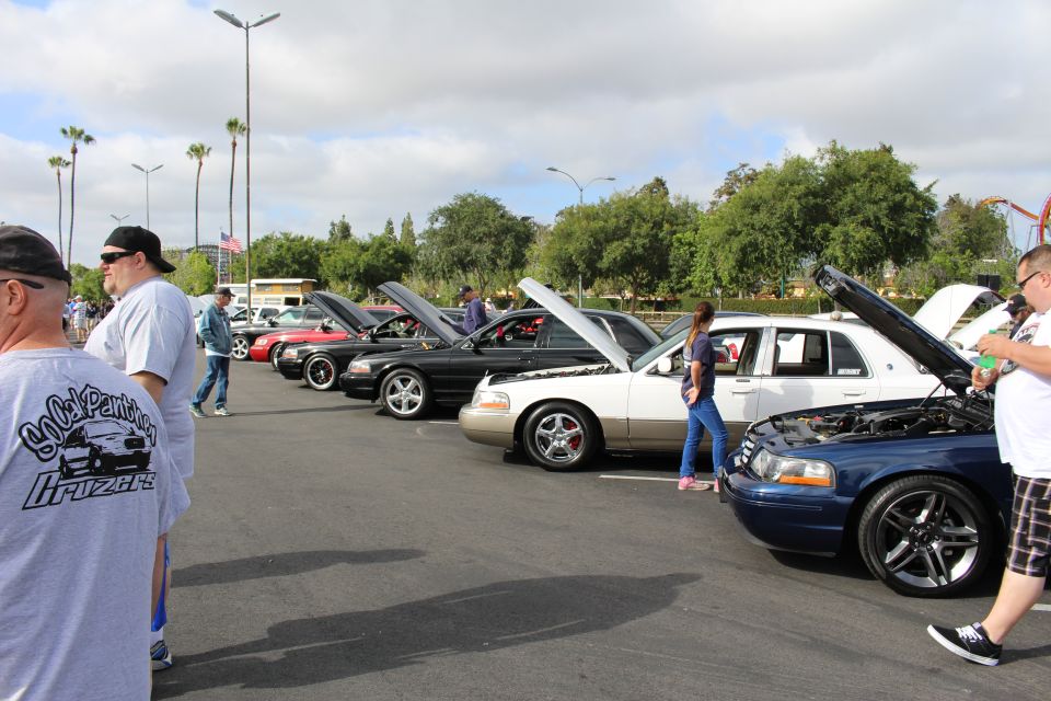 Row of Ford and Mercury sedans with open hoods and attendees