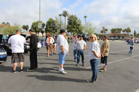 2003 Ford Crown Victoria - group of casually dressed people stand and chat in a parking lot, one woman looking back toward the camera.
