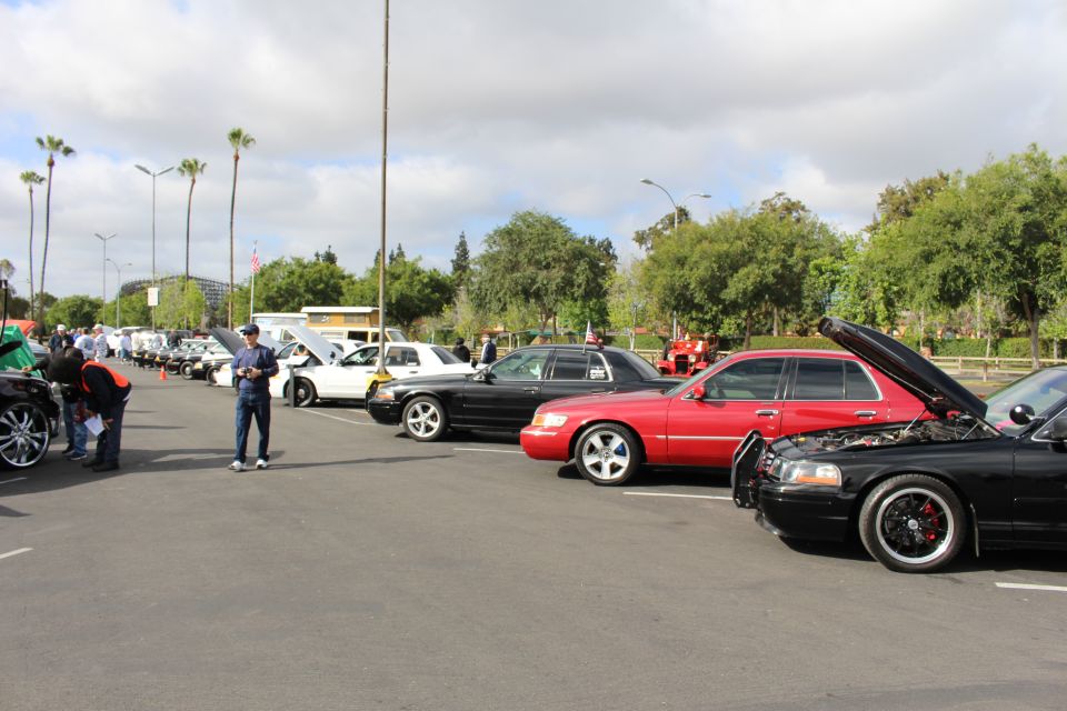 Long row of sedans at a parking-lot car show under cloudy sky