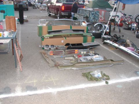 1973 Ford Ranchero - Various car parts are displayed on the ground at an outdoor market.