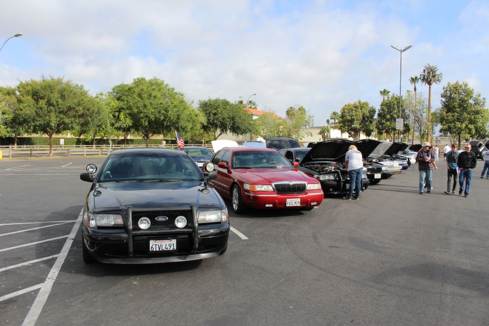 Black Ford sedan with push bar and red sedan lined up at a car show