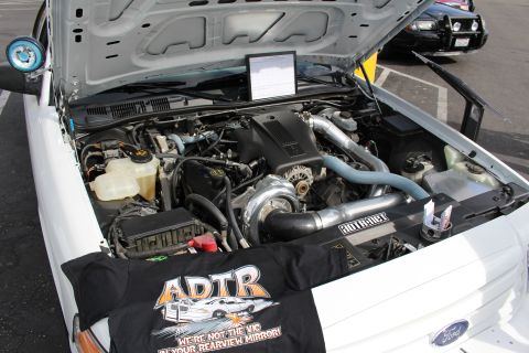2003 Ford Crown Victoria - Close view of a white car's supercharged V8 engine bay with intercooler piping and an ADTR draped banner.