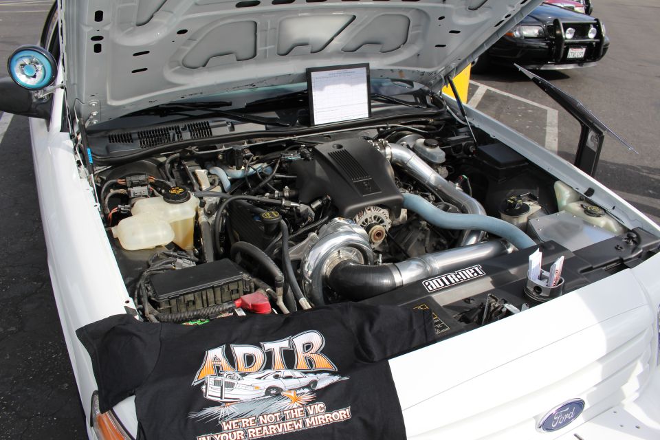 Close-up of a supercharged engine bay with ADTR banner in a white car