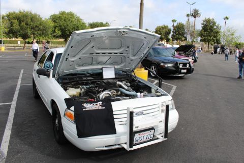 2003 Ford Crown Victoria - white Ford Crown Victoria sedan displayed with its hood up at an outdoor parking-lot car show, a black Ford sedan behind it.