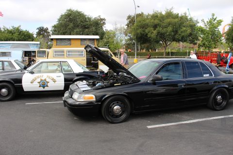2003 Ford Crown Victoria - black Ford Crown Victoria with steel wheels and open hood parked next to a white California Highway Patrol cruiser.