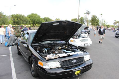 2003 Ford Crown Victoria - black Ford Crown Victoria with its hood up parked in a lot, with show attendees and other cars in the background.