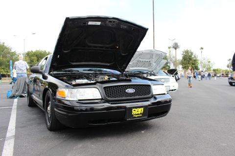 2003 Ford Crown Victoria - Front three-quarter view of a black Ford Crown Victoria with raised hood and a Car Craft Magazine placard at a car show.
