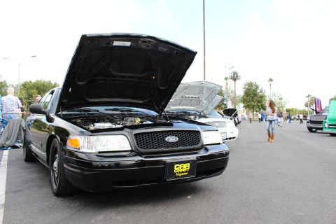 2003 Ford Crown Victoria - black Ford Crown Victoria sedan with raised hood and a Car Craft Magazine sign displayed at an outdoor car show.