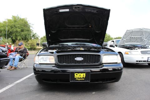 2003 Ford Crown Victoria - Head-on view of a black Ford Crown Victoria with raised hood and a Car Craft Magazine placard on the grille.