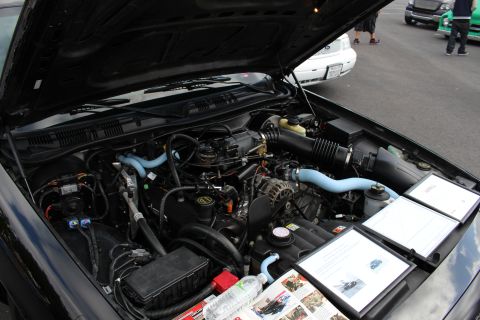 2003 Ford Crown Victoria - Engine bay of a Ford sedan showing the V8, alternator, and air intake with informational display boards set on the fender.