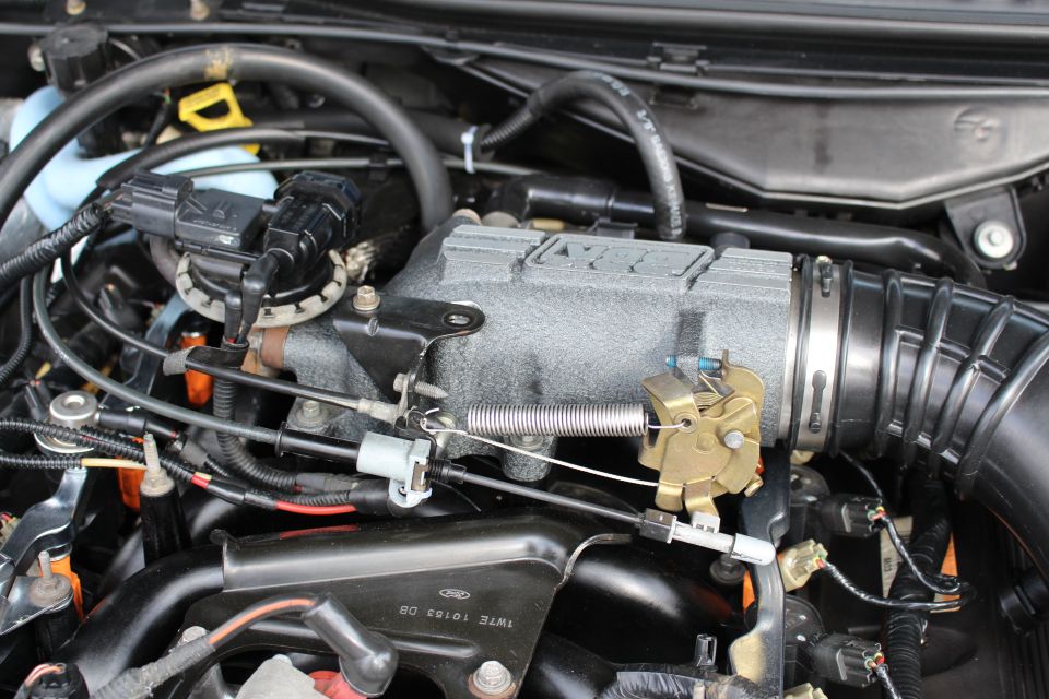 Close-up of an intake manifold and throttle linkage in an engine bay