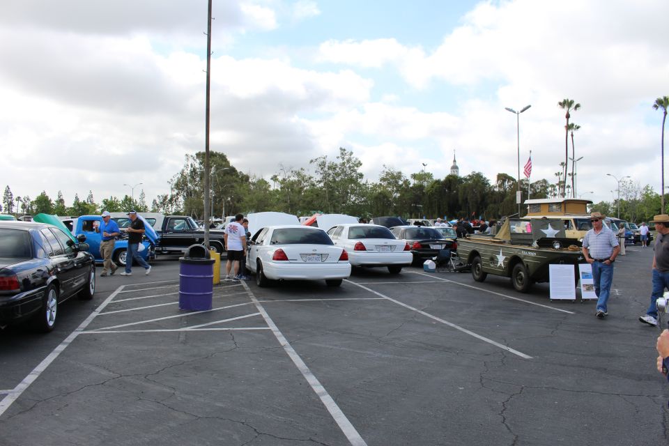 Parking-lot car show with a white sedan and an olive-drab military vehicle