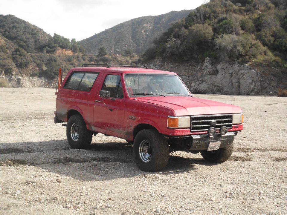1988 Ford Bronco parked on dirt road with mountains in background