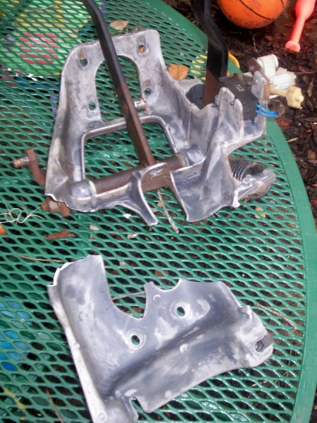 1988 Ford Bronco - A disassembled vehicle pedal assembly lies on a green mesh table outdoors.
