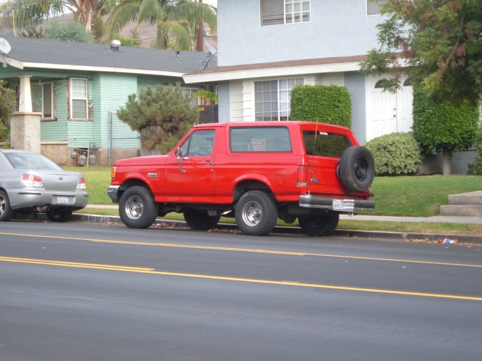 Red 1988 Ford Bronco parked curbside, side view