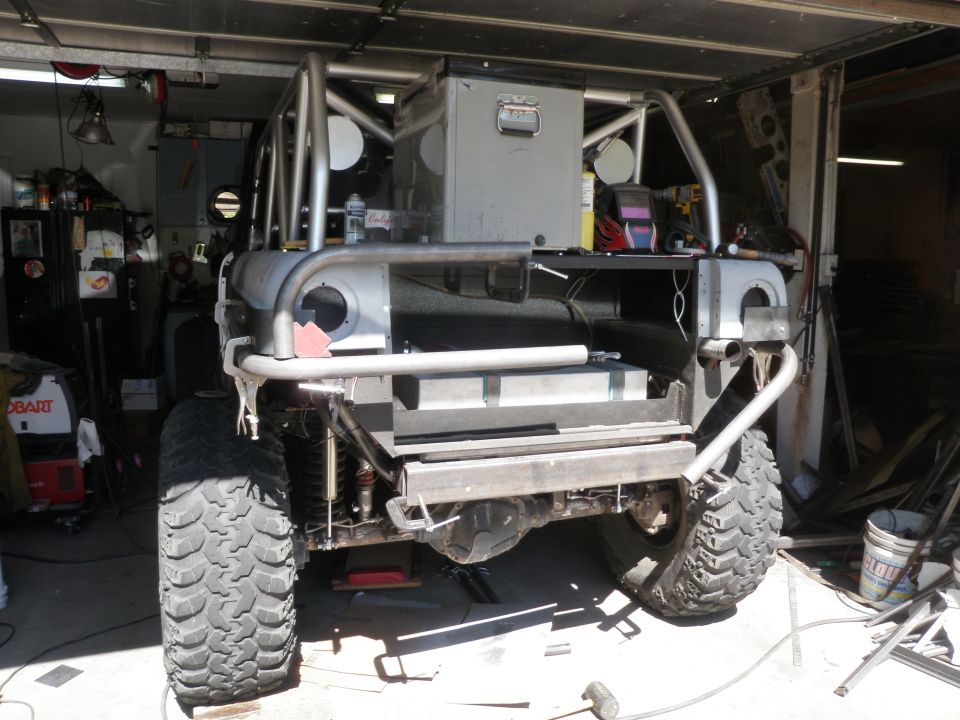 Custom off-road vehicle rear view with roll cage and large tires in a garage
