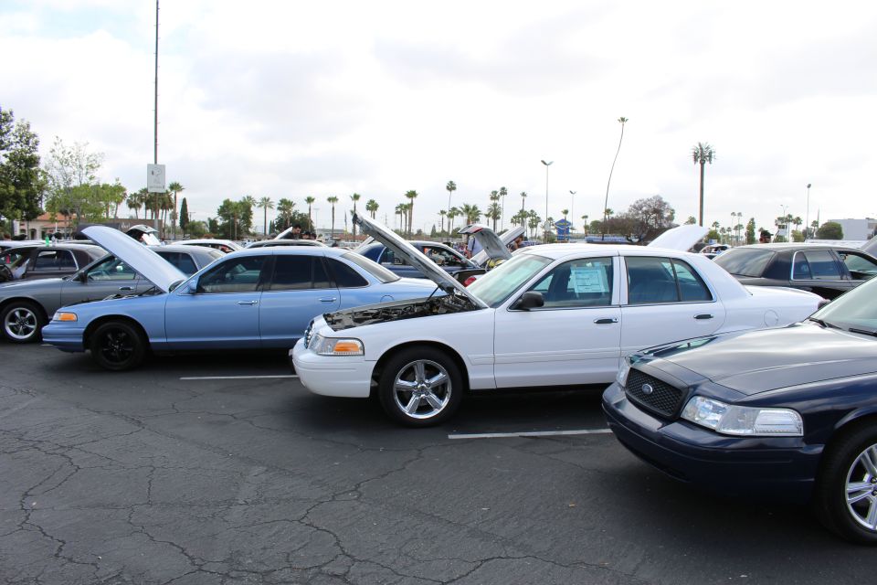 Light-blue, white and navy full-size sedans with open hoods at a show