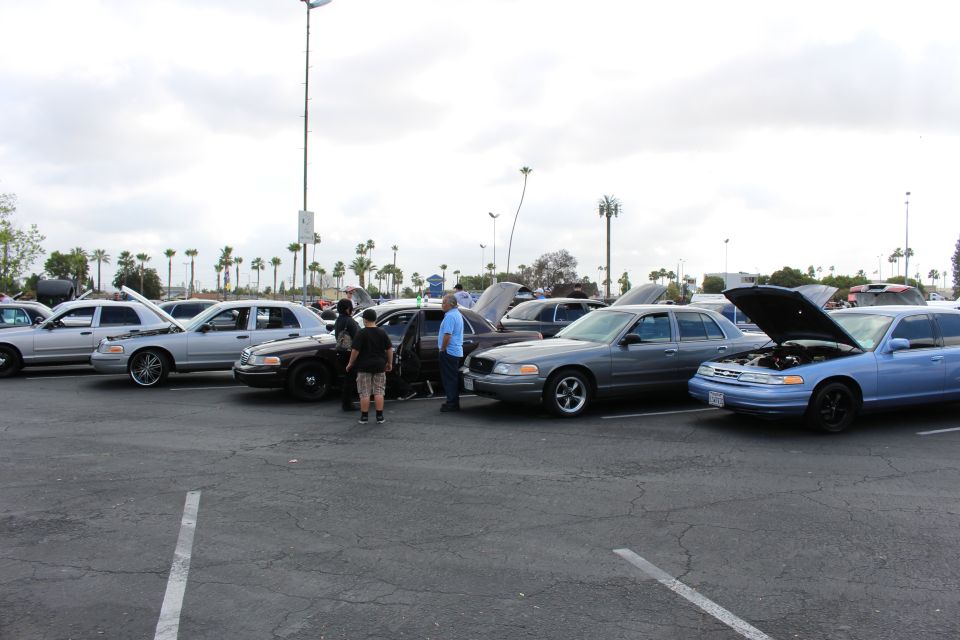 Brown, gray and blue sedans with people inspecting them at a car show