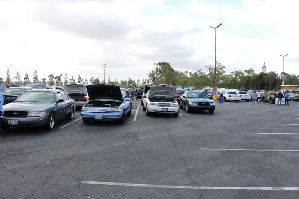 Gray, blue and white full-size sedans with open hoods in a car show lot