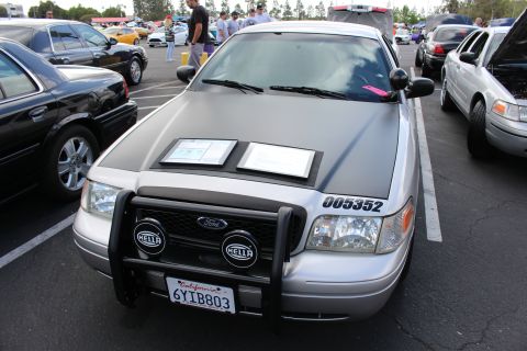 2003 Ford Crown Victoria - silver Ford sedan fitted with a front push bar, Hella driving lights and display cards sits showing California plate 6YIB803.