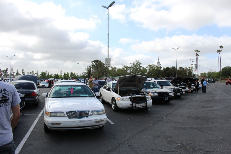 White Mercury and other sedans lined up with open hoods at an outdoor car show