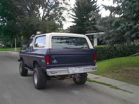 1979 Ford Bronco - This Ford Bronco is parked on a suburban street, showing its rear profile and off-road tires.