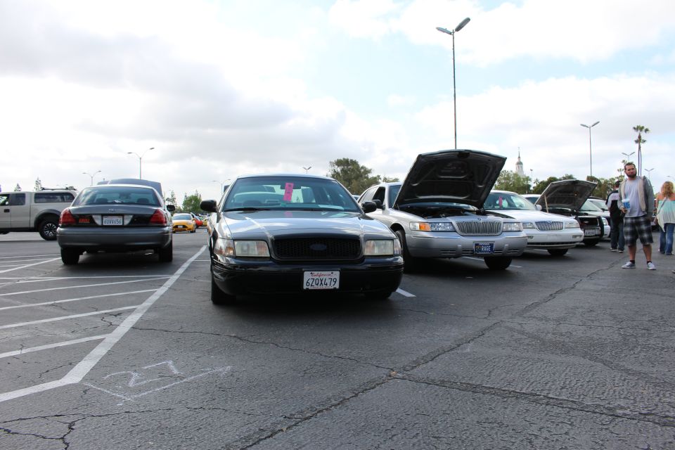 Black Ford Crown Victoria parked head-on among Panther sedans at car show