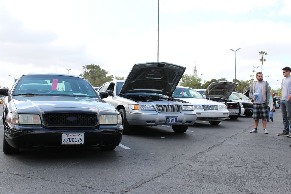 Black Crown Victoria and silver Mercury sedans lined up at outdoor car show