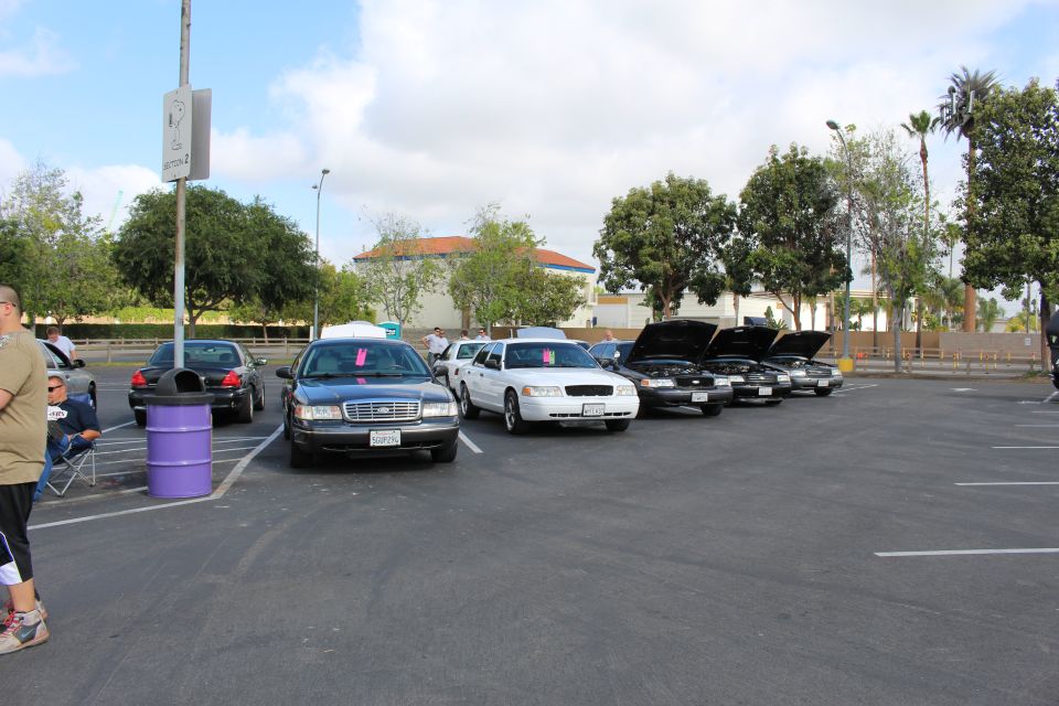 Black, gray and white sedans parked in a row in a large parking lot