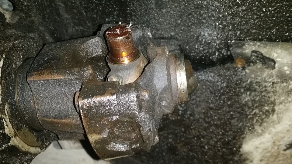 close-up of a greasy driveshaft u-joint with a worn-out bearing cap