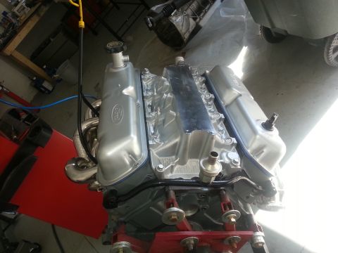 1994 Ford Bronco - A silver Ford V8 engine is mounted on a red stand, ready for installation.