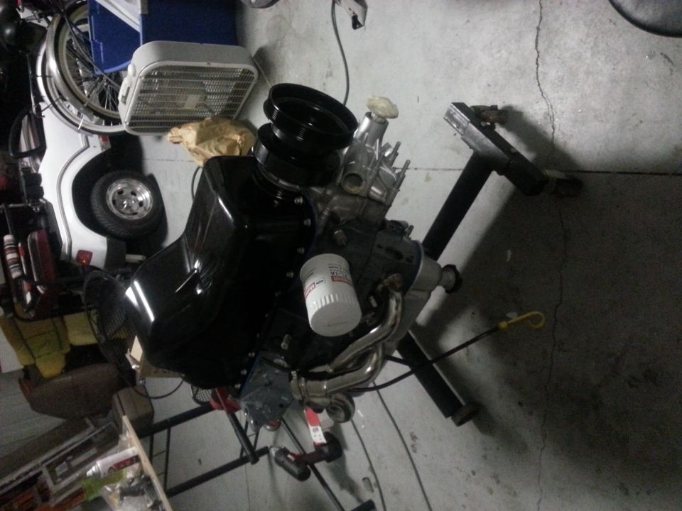 Black engine on a stand with an oil filter and pulleys
