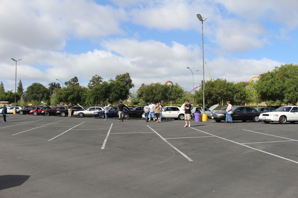 Wide empty parking lot with a distant row of cars and people at a meet