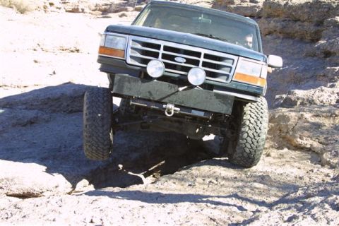 1994 Ford Bronco - This 1992 Ford Bronco is shown tackling a challenging off-road course with its front wheels angled over rocks.