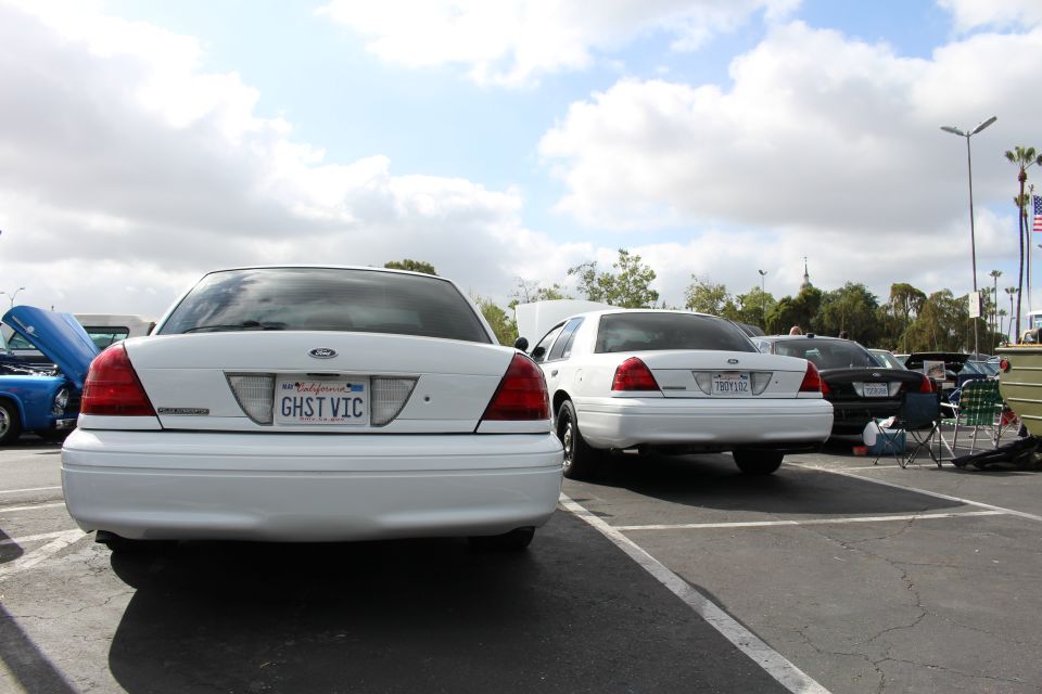 Rear of white Ford sedan with GHST VIC California plate at outdoor car show