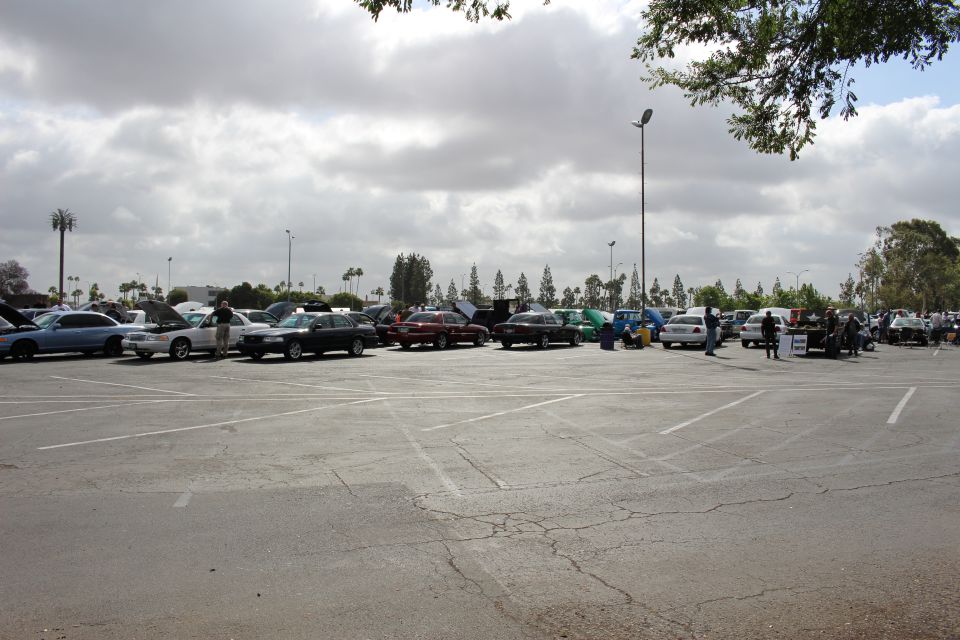 Distant row of show cars across a wide cloudy parking lot