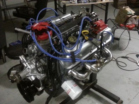 1994 Ford Bronco - A V8 engine is shown on an engine stand, a red distributor cap and blue spark plug wires.