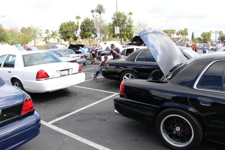 Black sedans with open hood and white sedan in a busy show lot