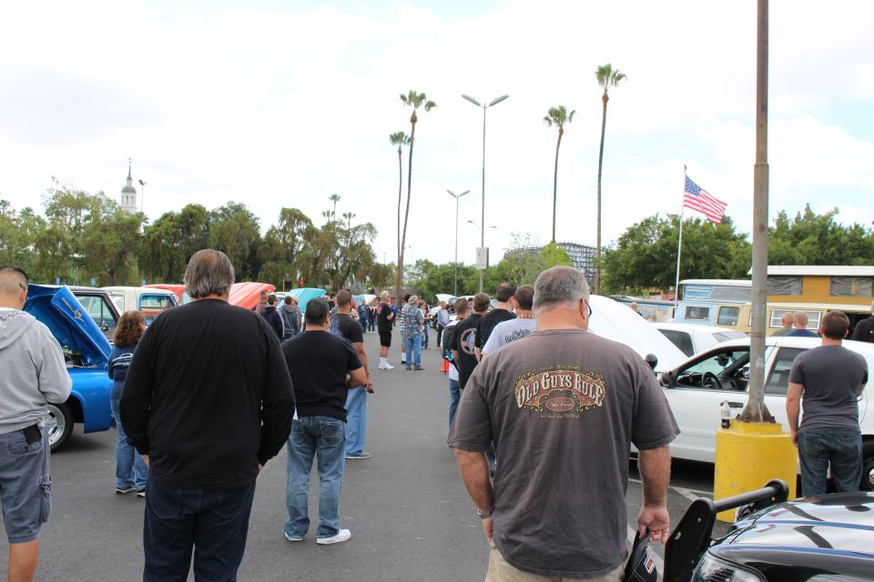 Crowd of spectators viewing show cars under palm trees and US flag