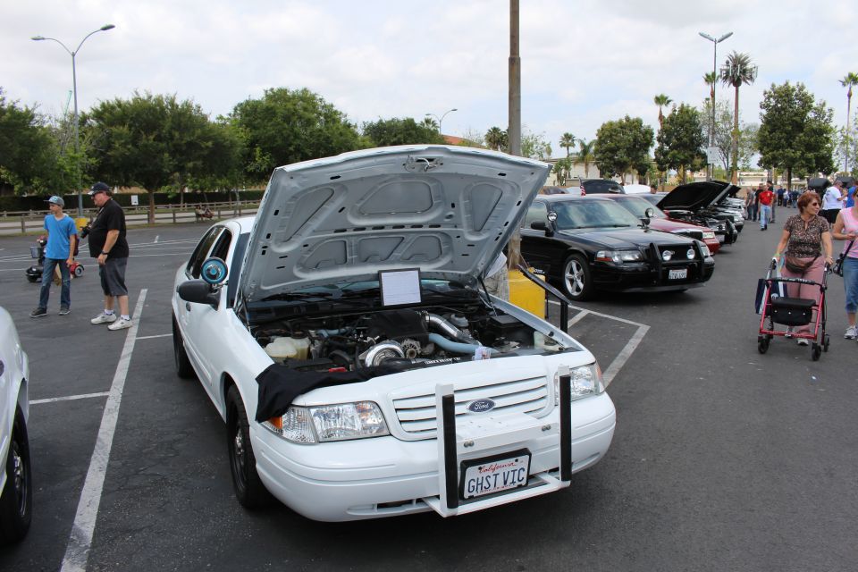 Front of white Ford sedan with open hood and turbo engine at car show