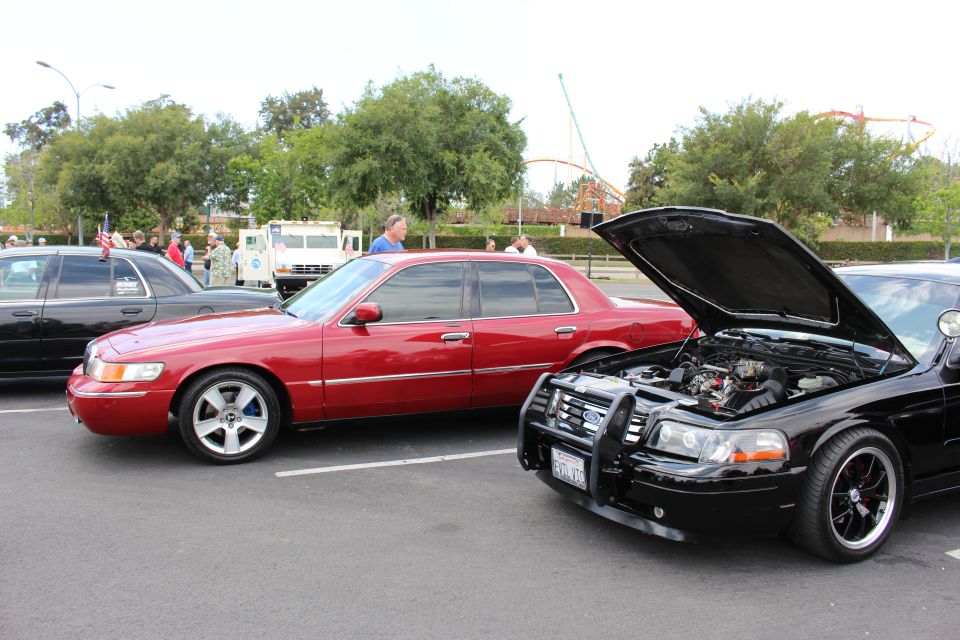 Red Mercury sedan next to black Ford sedan with brush guard and open hood
