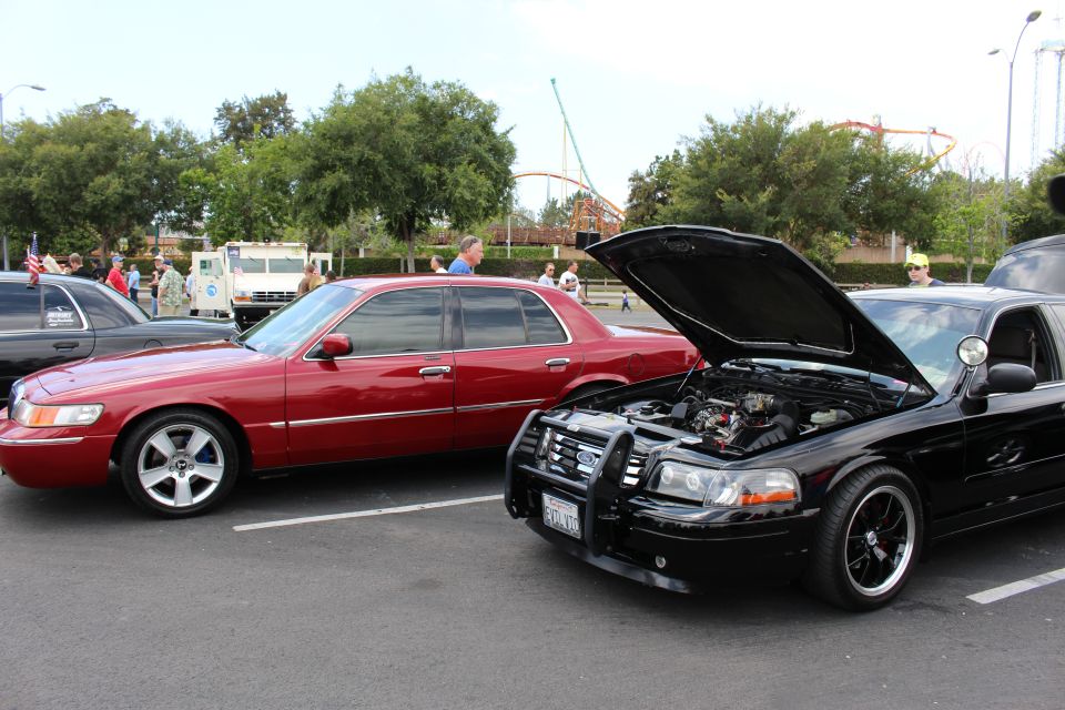 Red Mercury sedan and black sedan with open hood and brush guard at meet