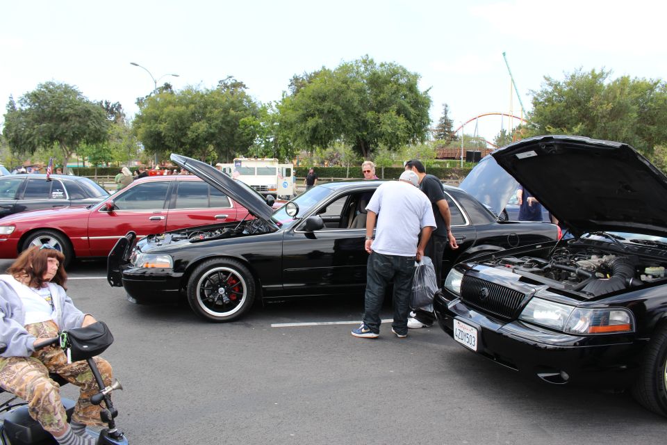 Black Mercury Marauder sedans with hoods up at an outdoor parking-lot car show