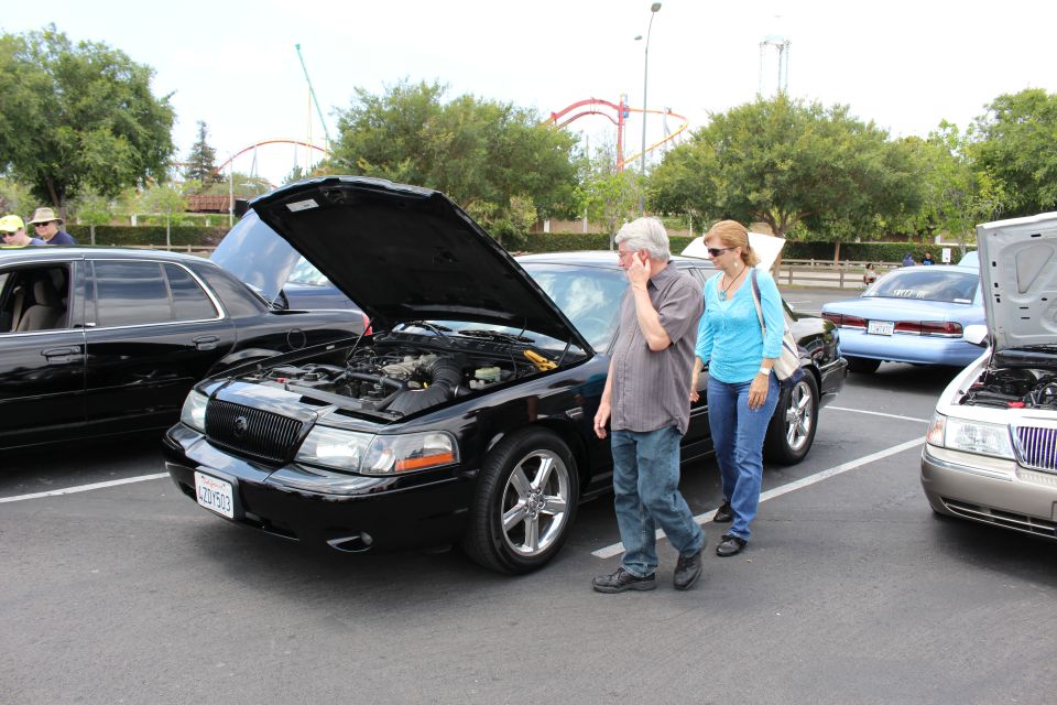 Black Mercury Marauder sedan, hood open, couple standing beside it