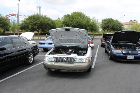 Gold Mercury Grand Marquis seen head-on with hood raised in a parking lot