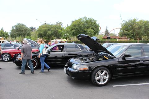Black Mercury sedan with hood up at a car show, people walking past