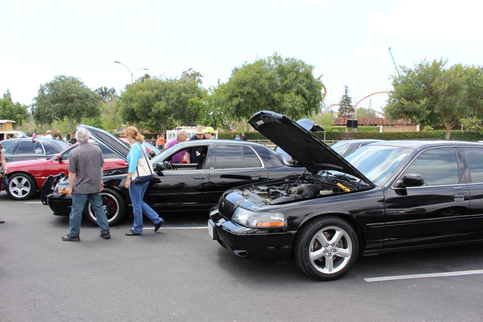 Black Mercury sedan with hood up at a car show, people walking past