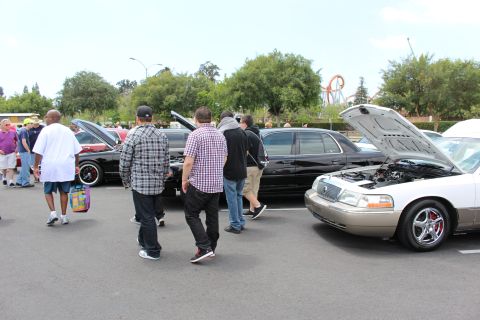 Crowd of attendees walking among black and silver sedans at a car show