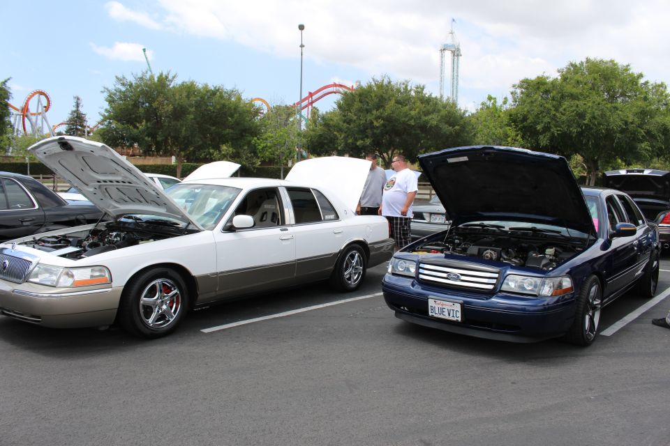 Two-tone Grand Marquis beside a blue Ford Crown Victoria, hoods up