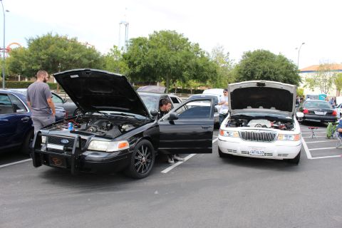 Black Ford Crown Victoria with push bar beside a white Lincoln, hoods up